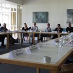 Eine Gruppe von Menschen sitzt an einem Tisch und spricht über Themen der Vereinten Nationen