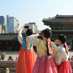 Tourismus und nachhaltige Stadtentwicklung - eine Herausforderung in Seoul, Südkorea Drei asiatische Touristinnen in koreanischen Kostümen machen Selfies im Palast in Seoul