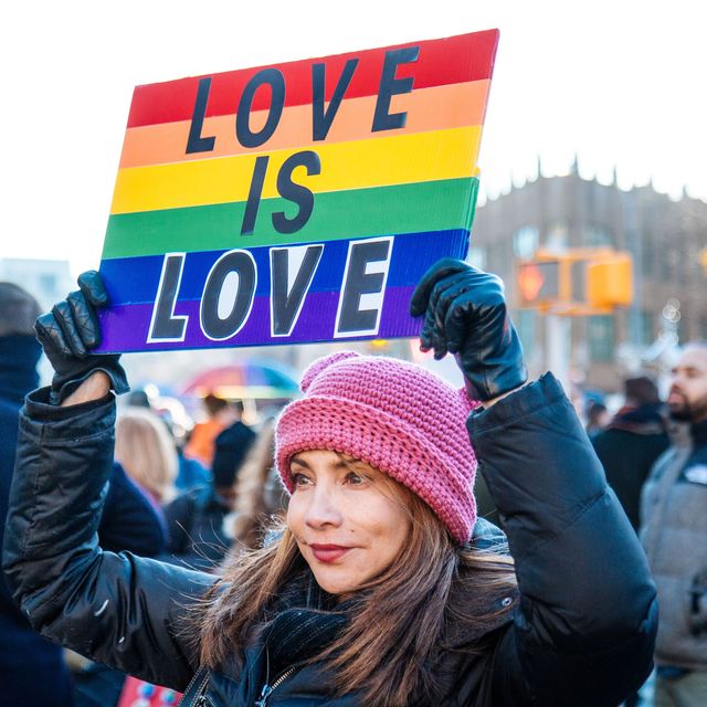 Eine Frau hält ein Plakat in Regenbogenfarben mit der Botschaft "Love is love".